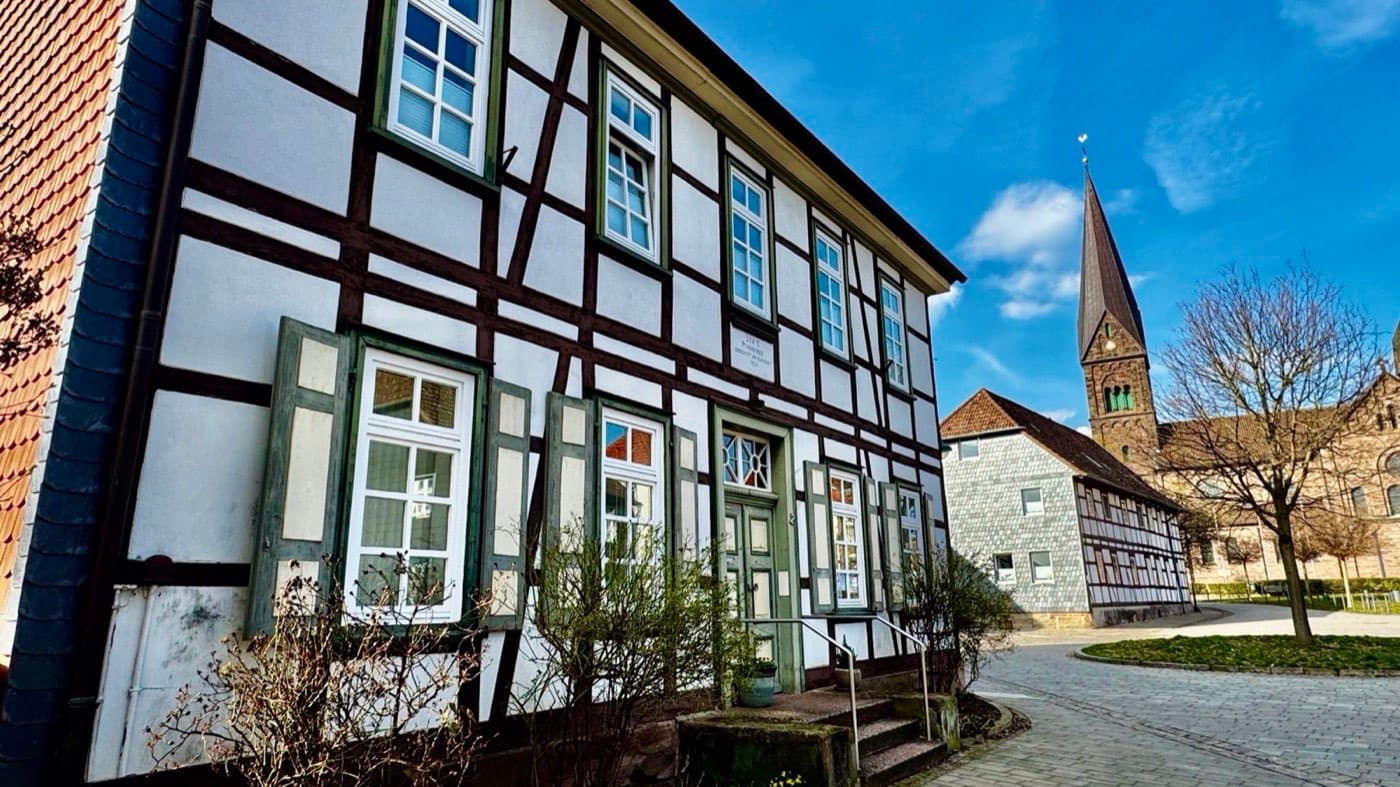 Historisches Fachwerkhaus mit Kirchturm an einem gepflasterten Platz in der Hildesheimer Altstadt