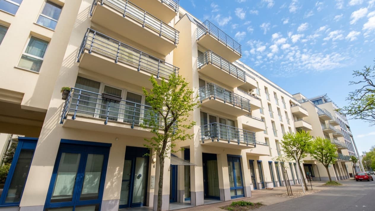 Modernes Mehrfamilienhaus mit Balkonen an einer sonnigen Straße